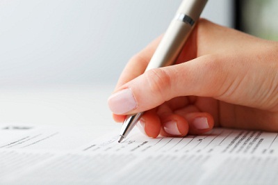 Frauenhand mit Stift und Formular